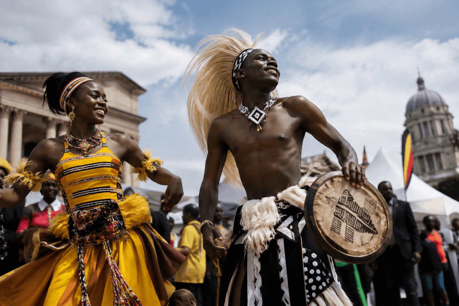 A photorealistic image of a vibrant Ugandan cultural festival taking place in a European city square. In the foreground, two performers dressed in traditional Ugandan attire smile as they dance, with one holding a decorated ceremonial drum. Behind them, a diverse crowd watches the celebration, while Ugandan flags, white festival tents, and historic European architecture create a backdrop that reflects the connection between Uganda and Germany. The image captures the intersection of culture, tourism, diplomacy, and international engagement, with no text visible.
